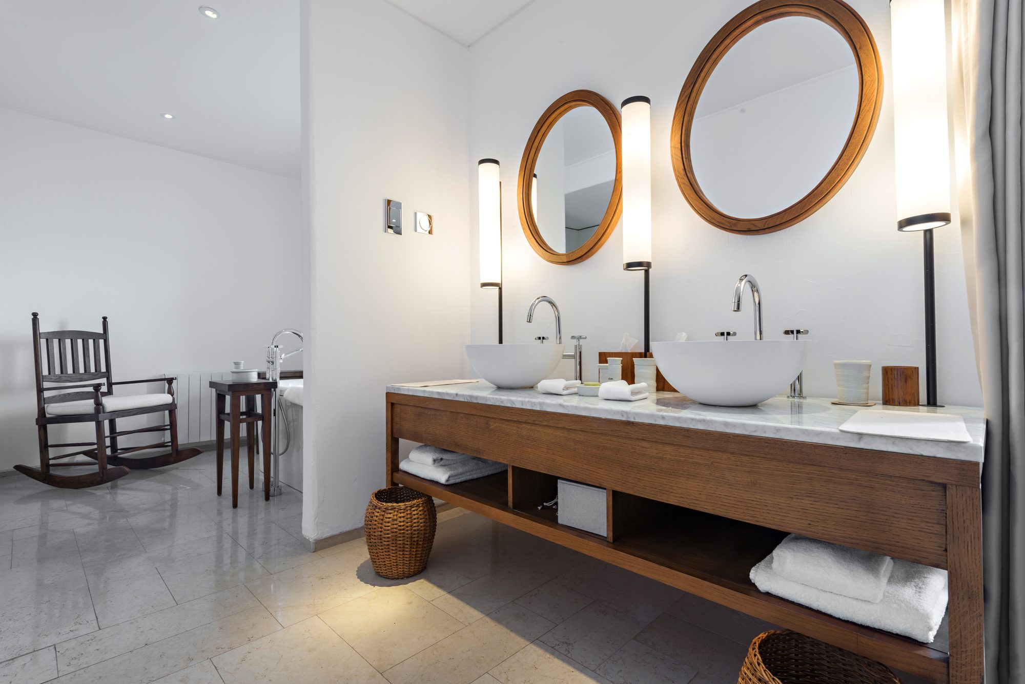 A remodeled bathroom with a long floating double vanity and round mirrors