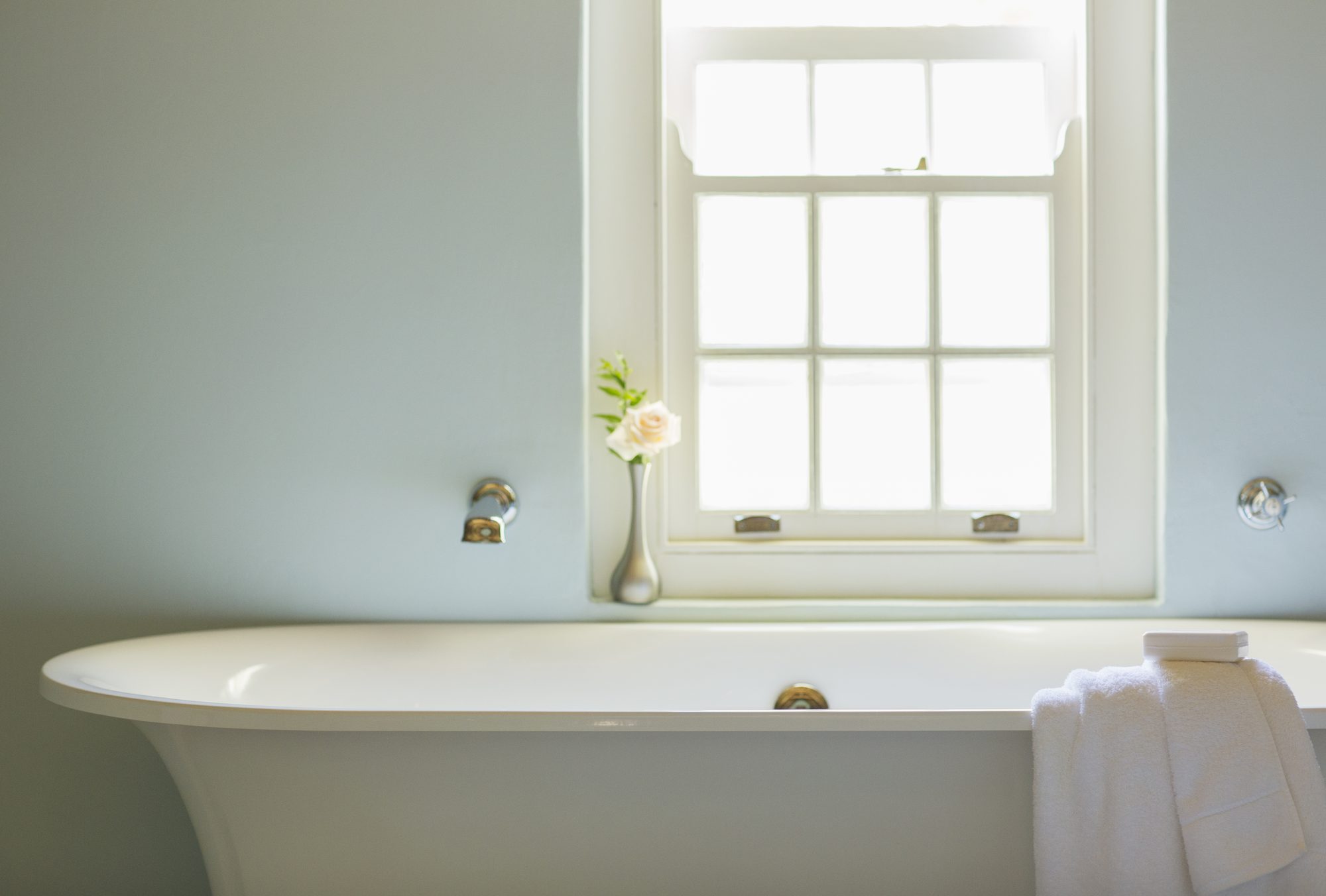 A remodeled bathroom with a teal feature wall and a freestanding soaking tub