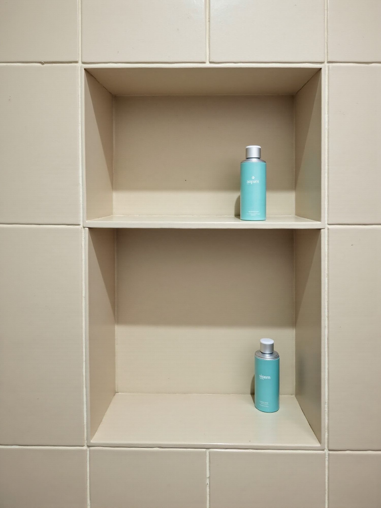 A tiled shower niche detail with teal glass accents