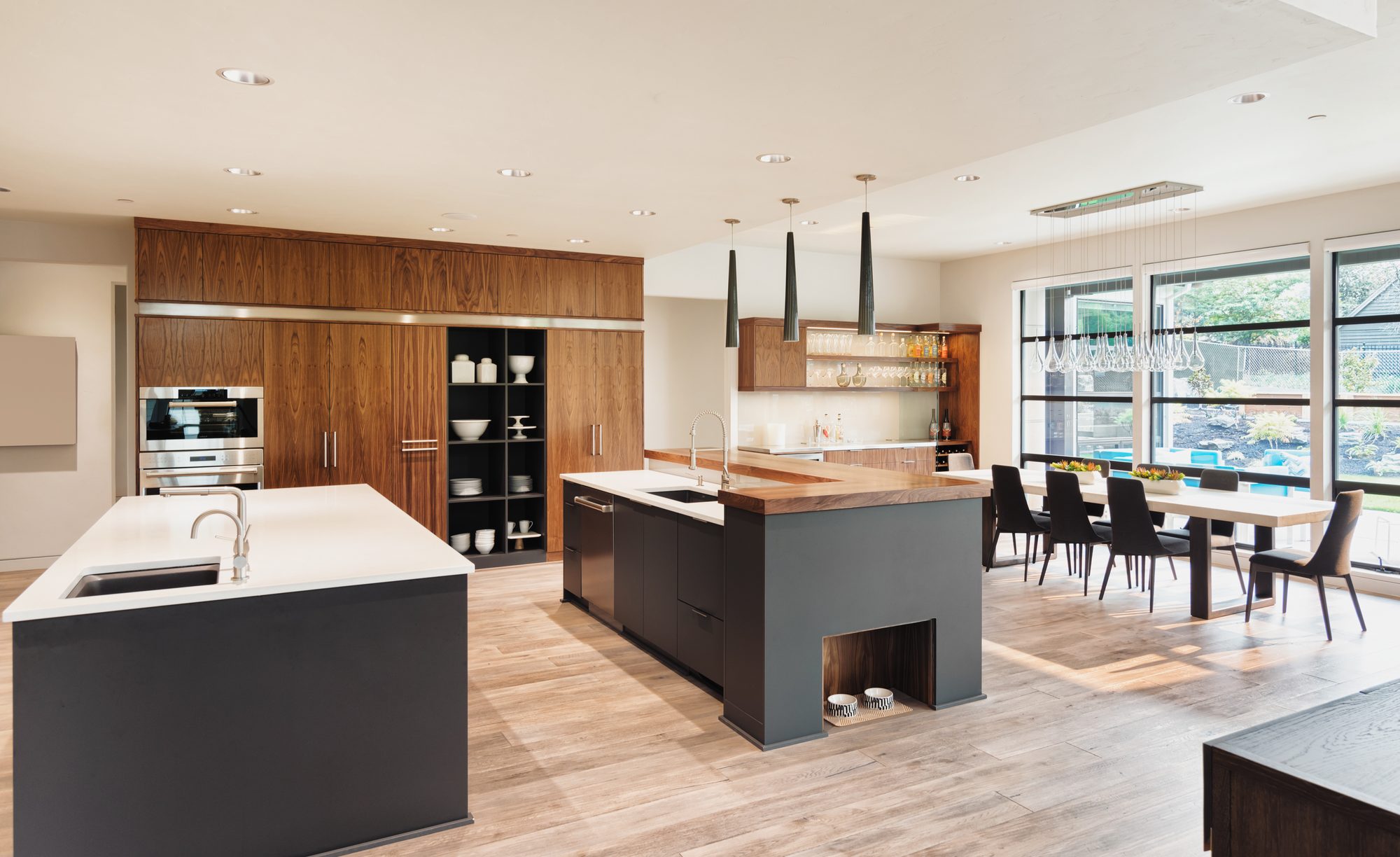 A kitchen with black cabinetry and a warm wood-topped island under pendant lights