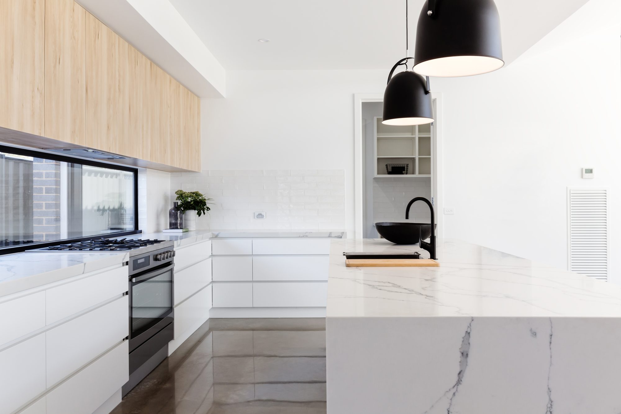 A modern white kitchen with a large marble-topped island