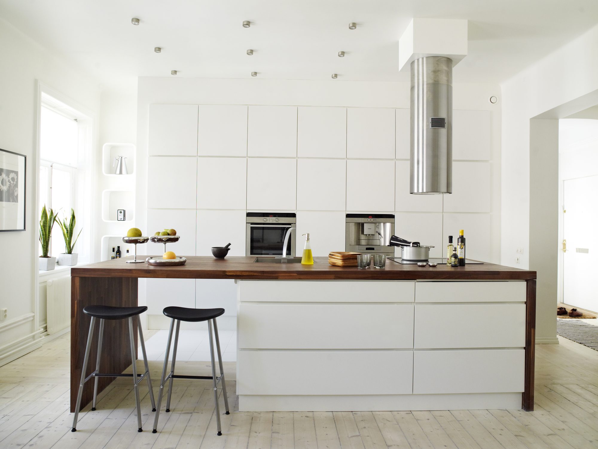 A bright white kitchen with a large center island and stainless appliances